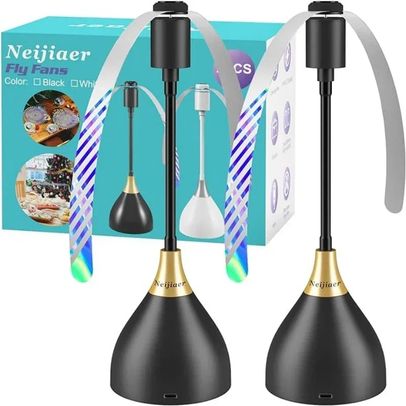 Two black OWOW Me portable fly-repelling fans for indoor and outdoor use, with gold accents and soft spinning blades, are displayed in front of their box, which shows the fans, features, brand name, color options, and easy storage highlights.