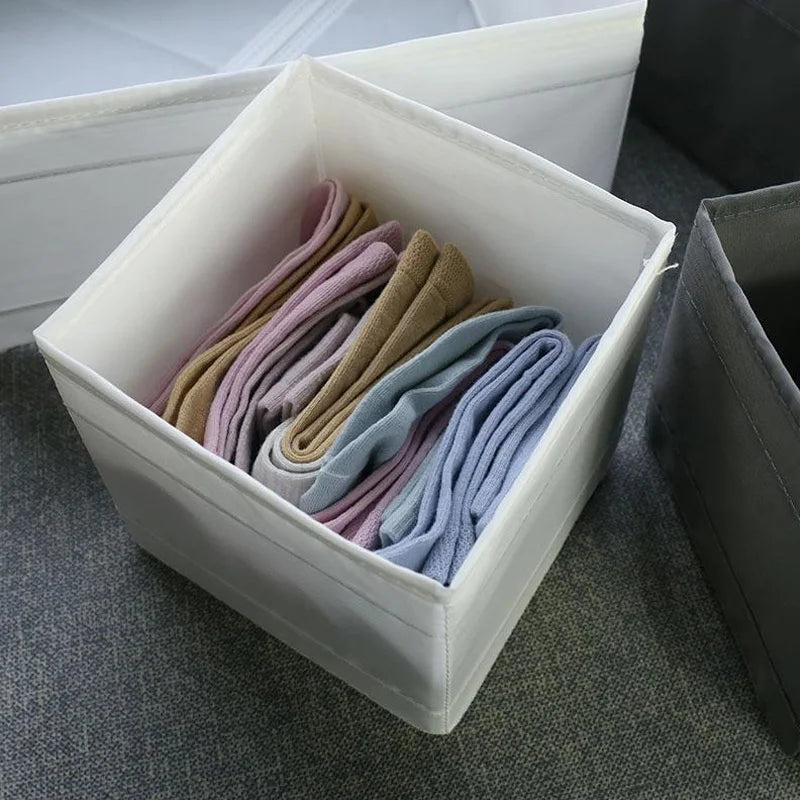 The OWOW Me Large Foldable Clothes Organizer in white neatly stores pastel socks—beige, pink, purple, and blue—upright in compartments on a gray surface.